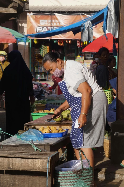 a group of people standing around a market, in the sun, balaclava, photo of a woman, working hard