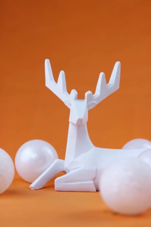 a close up of a figurine of a deer surrounded by balls, a marble sculpture, inspired by Rudolph F. Ingerle, in front of an orange background, white ceramic shapes, pearlescent white, full product shot