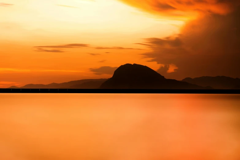 a large body of water with a mountain in the background, inspired by Frederic Edwin Church, pexels contest winner, romanticism, gradient orange, guwahati, islands on horizon, award winning landscape photo