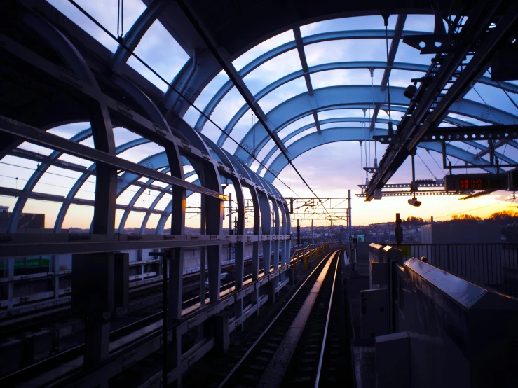 a train traveling down train tracks next to a train station, by Washington Allston, flickr, glass ceilings, going forward to the sunset, curved, 2000s photo