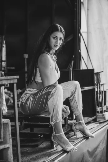 a black and white photo of a woman sitting on a bench, concert photo, full body photoshoot, wearing overalls, young woman with long dark hair