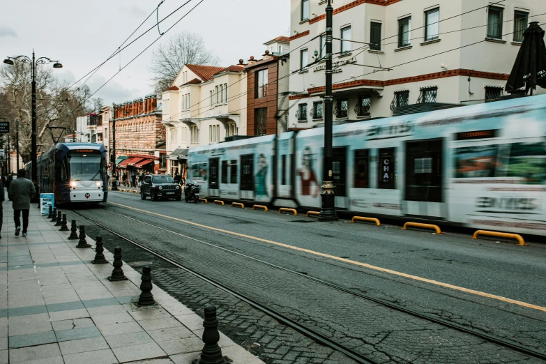 a train traveling down a city street next to tall buildings, by Niko Henrichon, pexels contest winner, art nouveau, istanbul, ( ( ( buses, traveling in france, grey