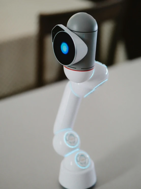 a robot that is sitting on a table, up-close, two arms, detailed product image, close up shot from the side