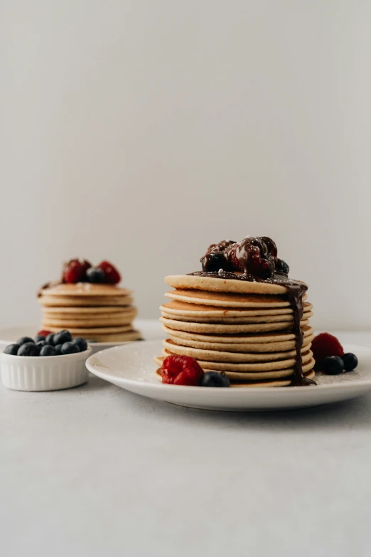 a stack of pancakes sitting on top of a white plate, inspired by Richmond Barthé, unsplash contest winner, berries, full product shot, sleek round shapes, chocolate