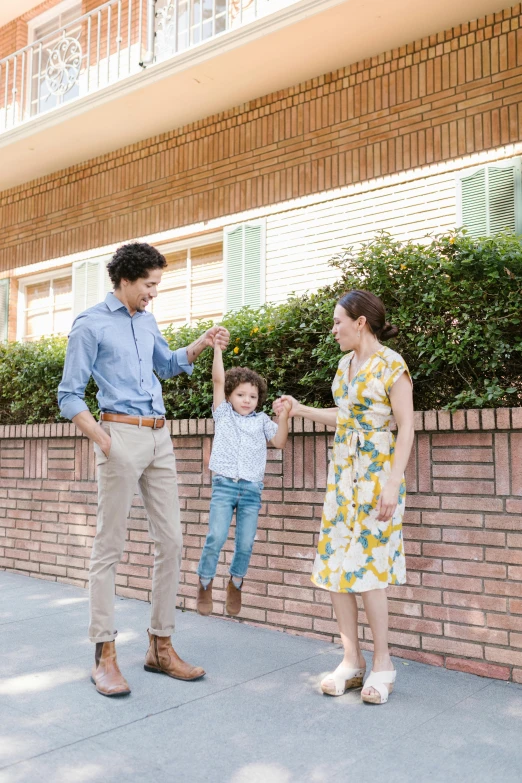 a man standing next to a woman and a child, pexels contest winner, standing outside a house, jumping towards viewer, nathan for you, summer street