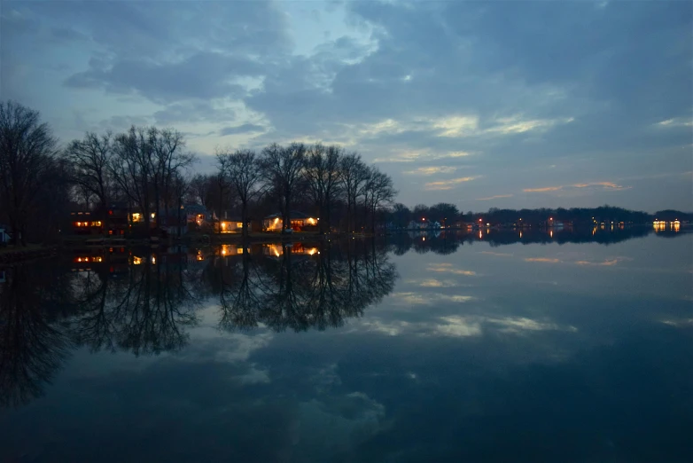 a large body of water surrounded by trees, by Washington Allston, pexels contest winner, hurufiyya, evening lanterns, amityville, mirrored, greg crewdson