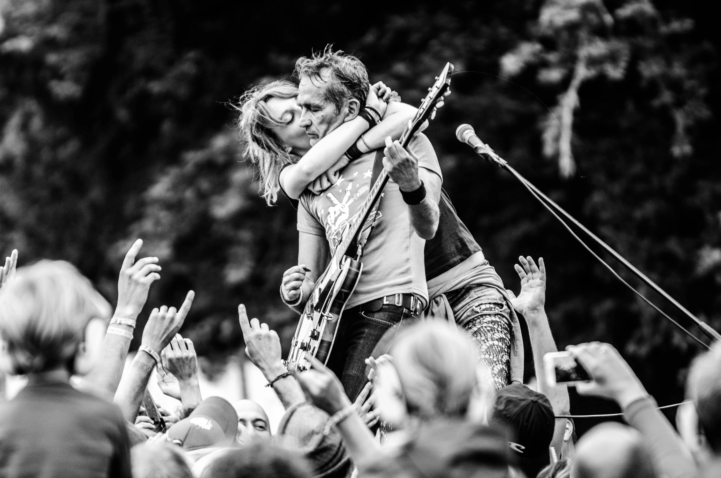 a group of people standing on top of a stage, a black and white photo, by Anato Finnstark, pexels, couple kissing, carrying a guitar, kieth thomsen, by greg rutkowski