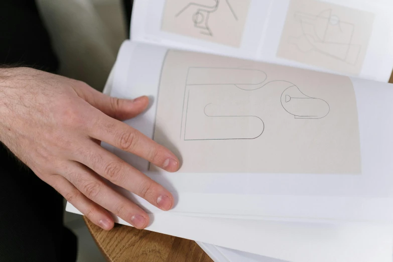 a person holding a piece of paper with drawings on it, a drawing, inspired by Louis Marcoussis, unsplash, classic product design, white tracing, ignant, engravings