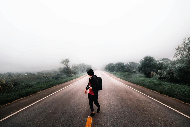 a person walking down a road on a foggy day, pexels contest winner, happening, with a backpack, gazing off into the horizon, 🚿🗝📝, wide full body