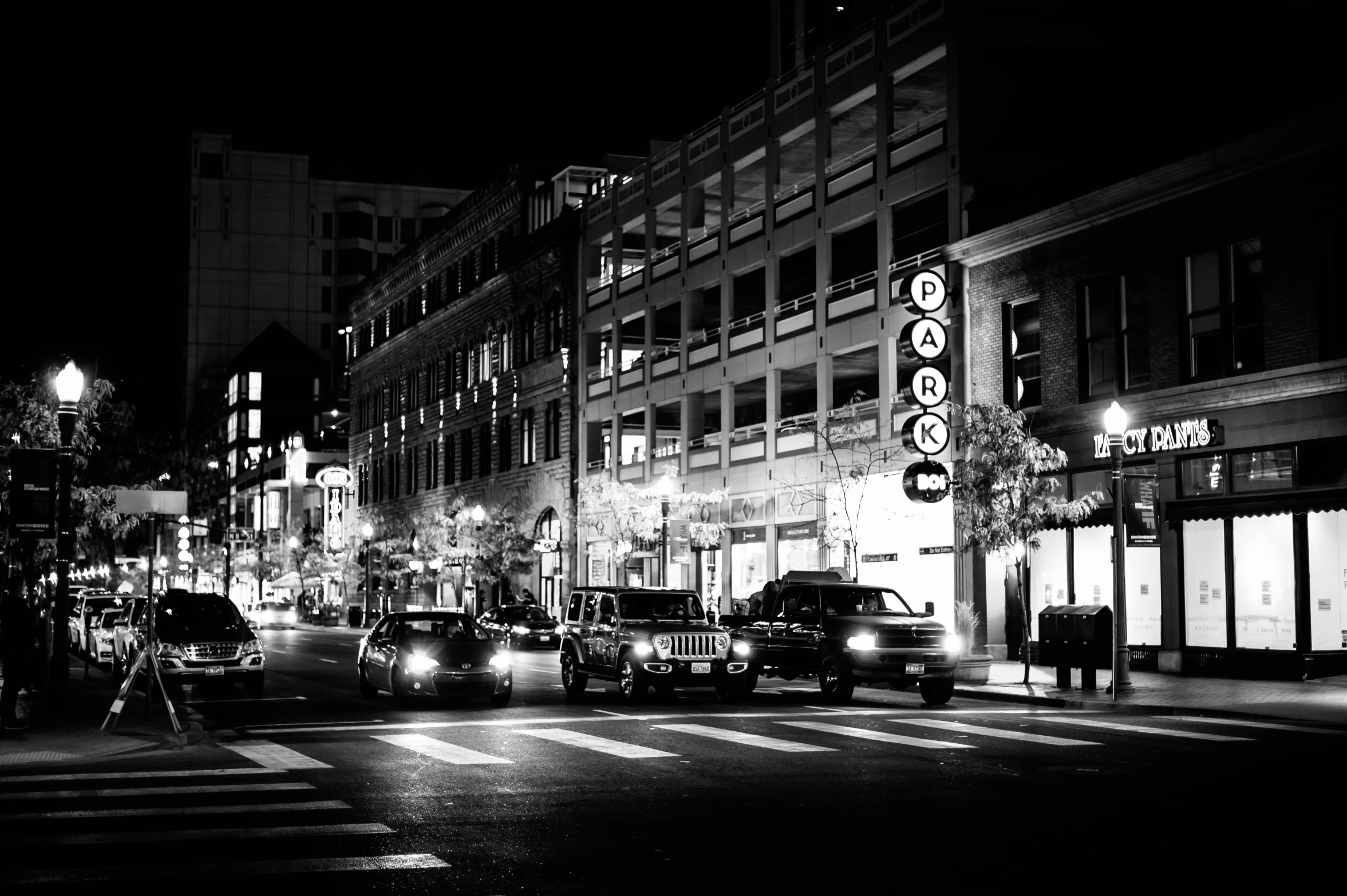 a black and white photo of a city street at night, by Dennis Flanders, pexels, square, cars, washington dc, japanese downtown