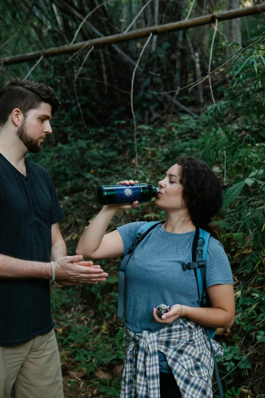 a man and a woman drinking water in the woods, pexels contest winner, aussie baristas, embarrassing, bottle, hispanic