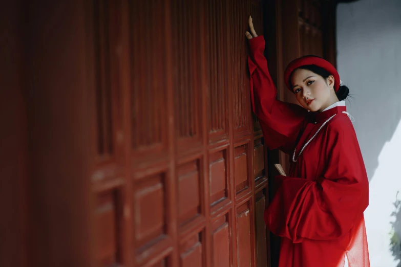 a woman in a red dress leaning against a door, inspired by Gu An, pexels contest winner, nun outfit, bao phan, girl wearing uniform, victorian style costume