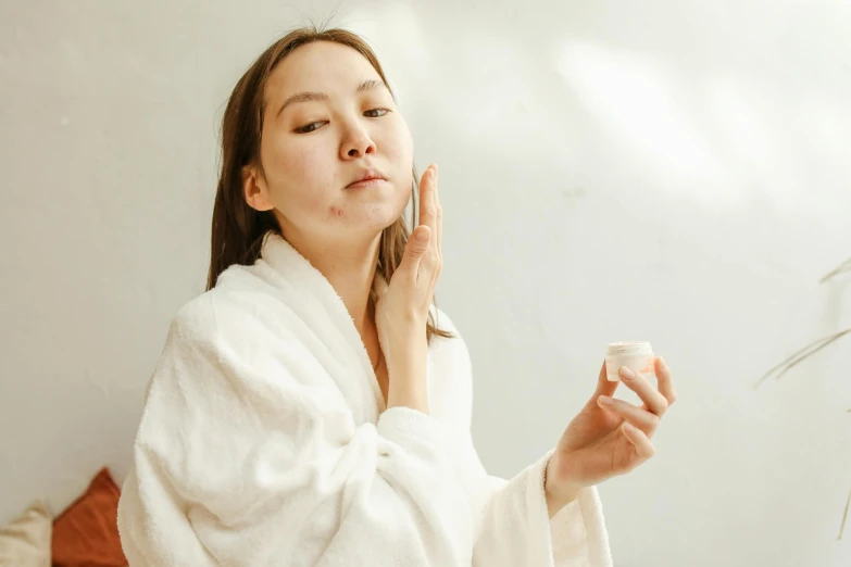 a woman in a bathrobe brushing her teeth, trending on pexels, happening, asian face, a plaster on her cheek, photoshoot for skincare brand, square facial structure