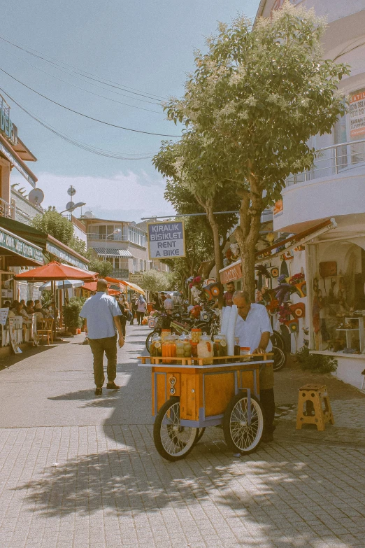 a group of people walking down a street, greece, shopping cart, near the beach, vintage aesthetic