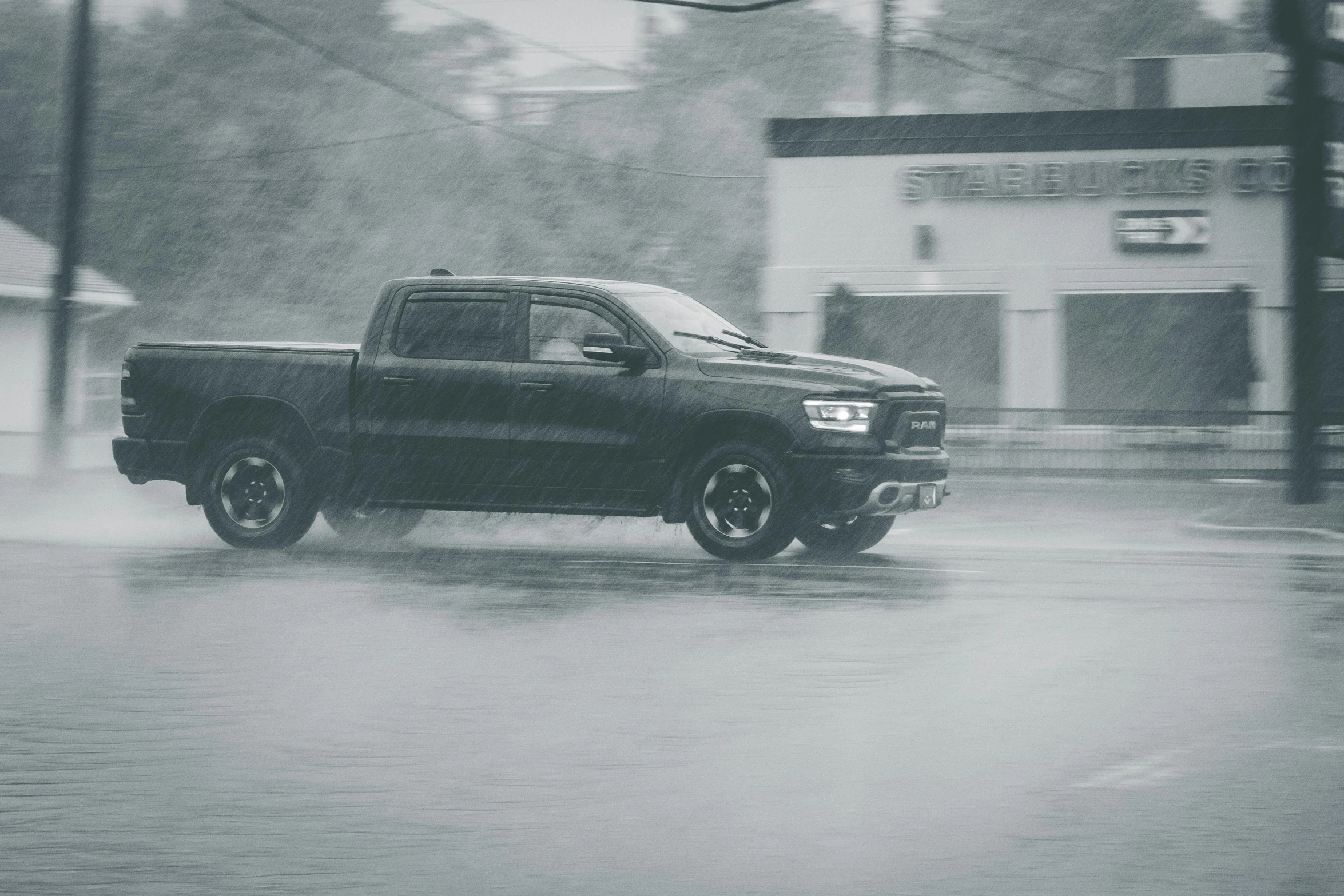 a black and white photo of a truck in the rain, a black and white photo, by Dan Frazier, pexels contest winner, battle ram, car drifting, photo render, hailstorm