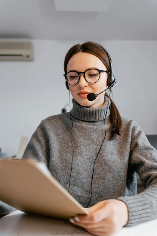 a woman sitting in front of a laptop wearing a headset, trending on pexels, grey, thumbnail, low quality photo, caucasian