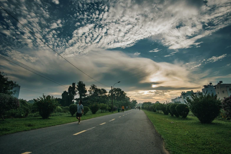 a person riding a skateboard down a road, by Jan Tengnagel, unsplash contest winner, huge clouds, bangladesh, a park, early in the morning