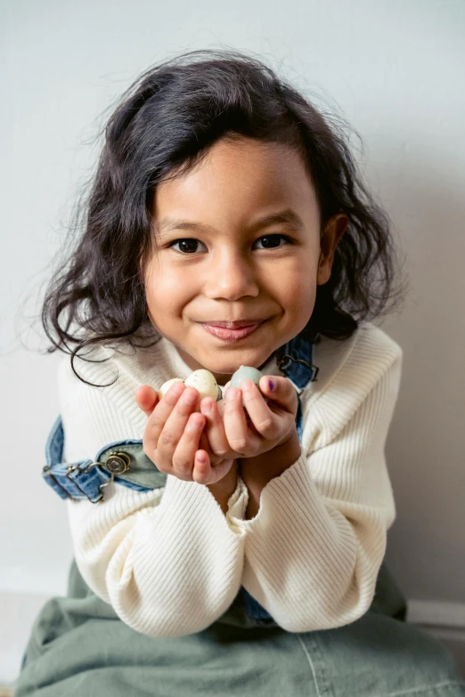 a little girl sitting on the floor with her hands together, inspired by Louis Le Nain, marshmallows, confident holding vegetables, holding an epée, inuit heritage