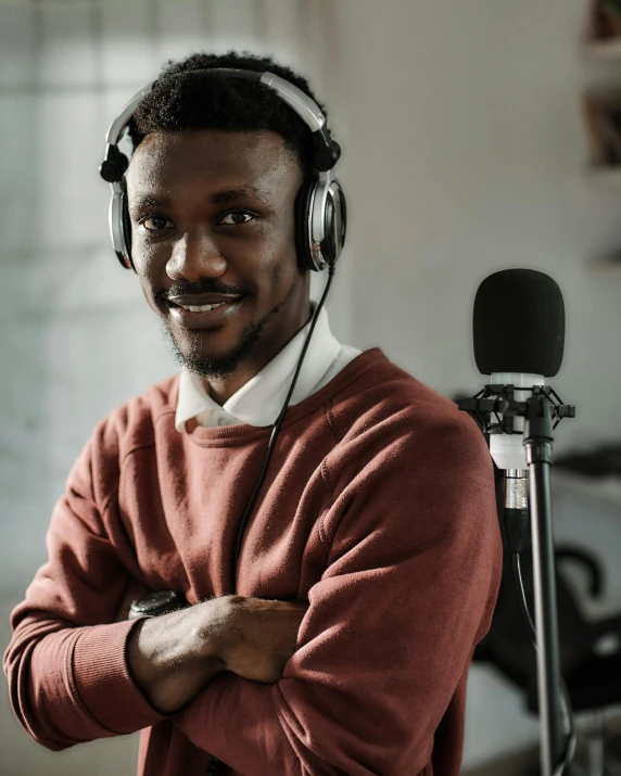 a man wearing headphones standing in front of a microphone, trending on pexels, lgbt, brown skinned, stood in a lab, friendly