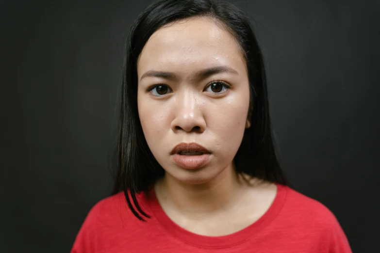 a close up of a person wearing a red shirt, pexels contest winner, hyperrealism, south east asian with round face, pout, her face is coated in a white, feeling of disgust