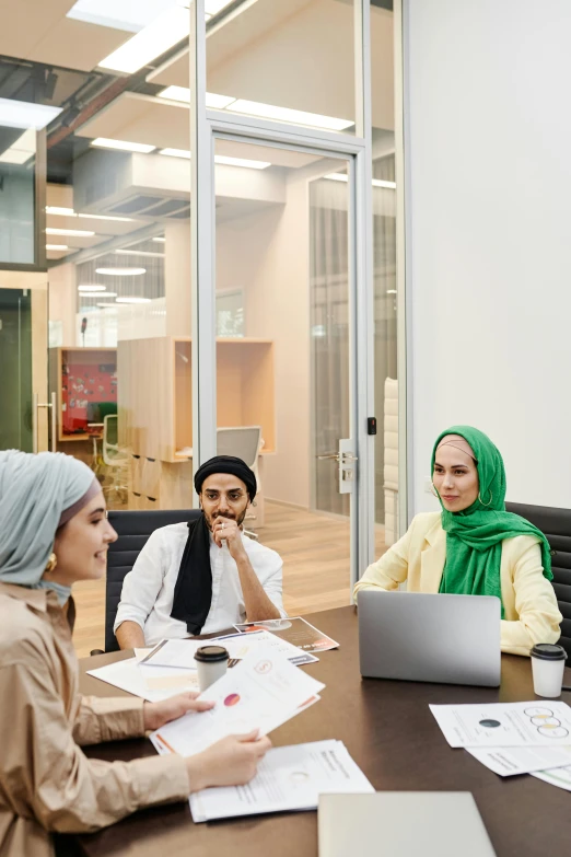 a group of people sitting around a table with laptops, by Maryam Hashemi, hurufiyya, islamic interior design, in an office, plain background, award - winning