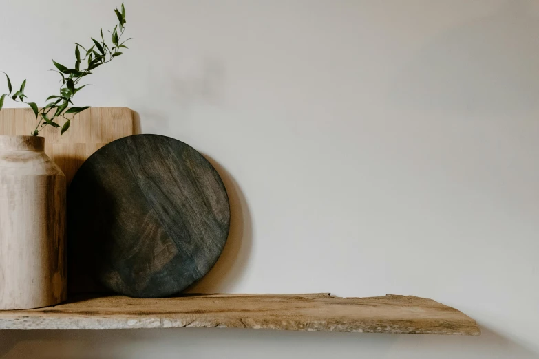 a couple of vases sitting on top of a wooden shelf, inspired by Richmond Barthé, trending on unsplash, chef table, holding a wood piece, looking to the side off camera, on textured disc base