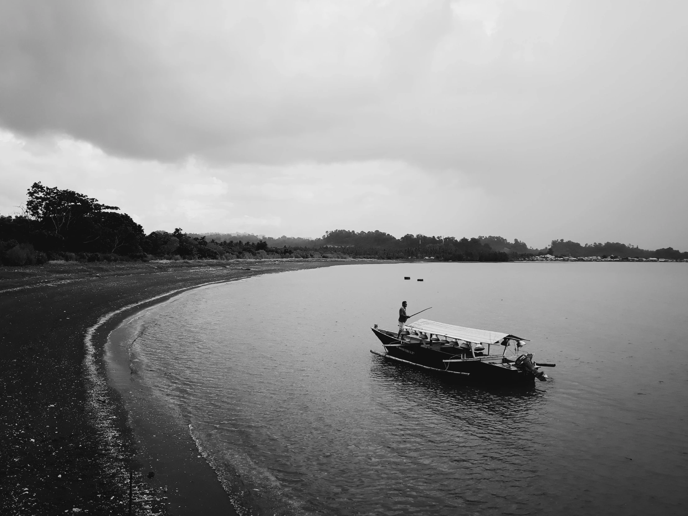 a black and white photo of a boat in the water, by Basuki Abdullah, unsplash, gloomy weather. high quality, guwahati, ffffound, seashore