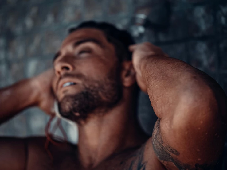 a shirtless man standing in front of a brick wall, by Adam Dario Keel, pexels contest winner, braided beard, soft lighting and focus, zyzz, morning glow