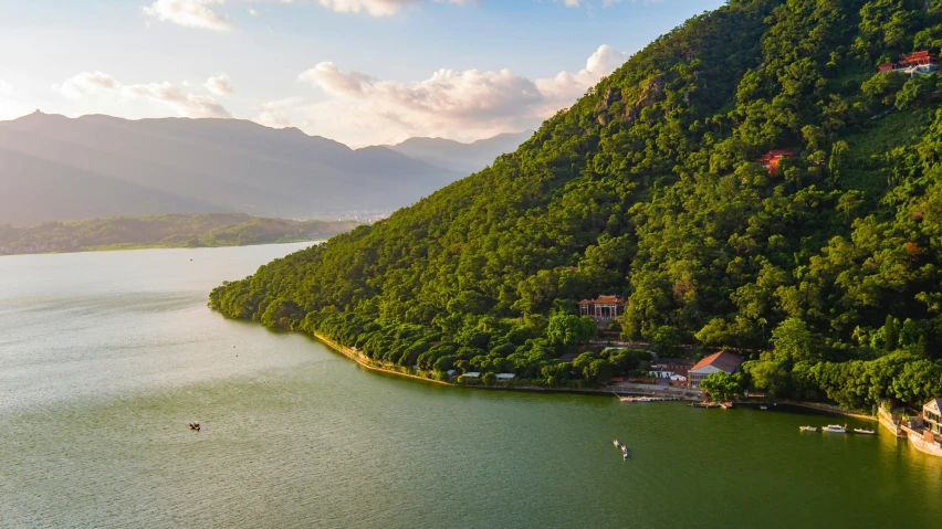 a large body of water surrounded by a lush green hillside, by Daniel Lieske, pexels contest winner, hurufiyya, vietnam, lake house, warm light, “ aerial view of a mountain