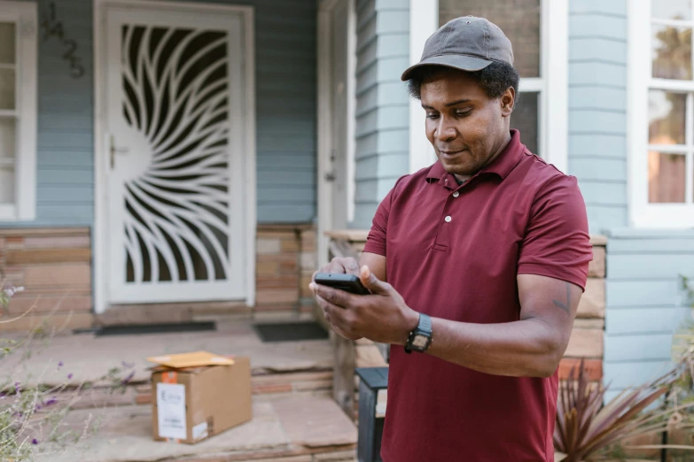 a man standing in front of a house looking at his cell phone, delivering packages for amazon, maroon, thumbnail, programming