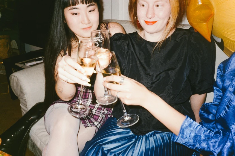 a couple of women sitting next to each other holding wine glasses, inspired by Nan Goldin, trending on pexels, kiko mizuhara, at the party, fiona staples and kinu nishimura, with white