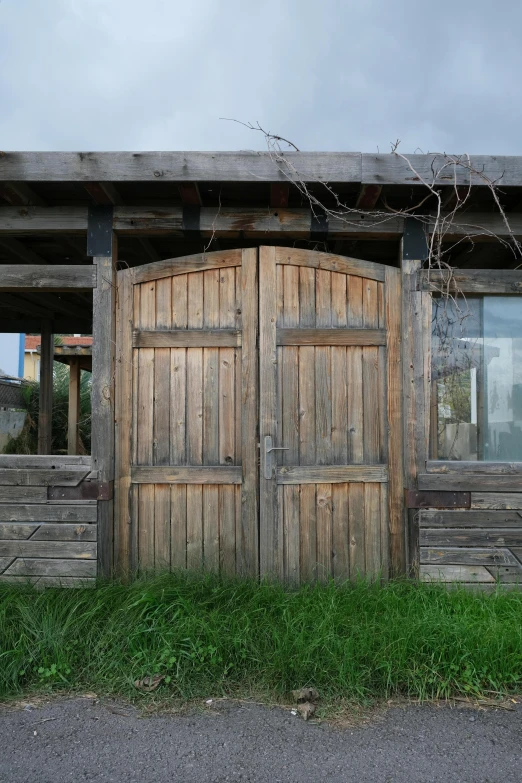 a couple of wooden doors sitting on the side of a building, on a farm, lawn, reclaimed lumber, arrendajo in avila pinewood