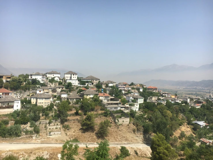 a view of a town from the top of a hill, riyahd cassiem, white buildings, landscape photo, sparsely populated