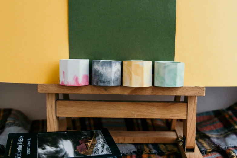 a stack of books sitting on top of a wooden table, inspired by Brice Marden, porcelain organic tissue, 4 cannabis pots, yellow and green scheme, product display