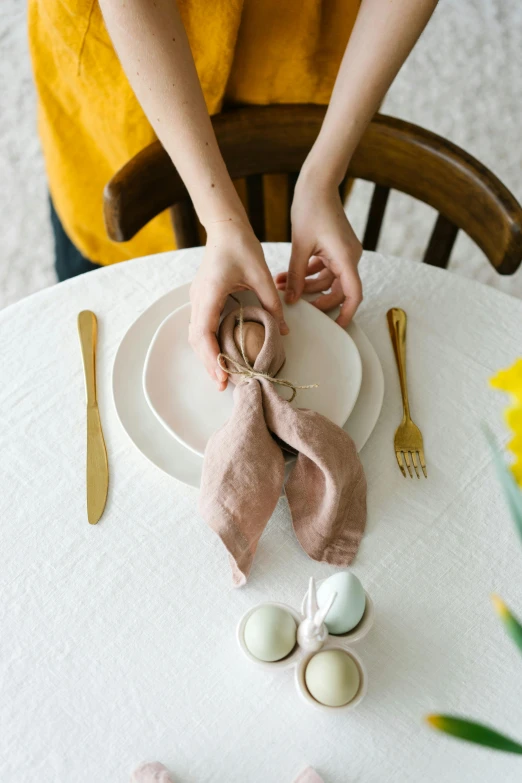 a person sitting at a table with a plate and napkin, easter, square, wearing a linen shirt, creating a soft