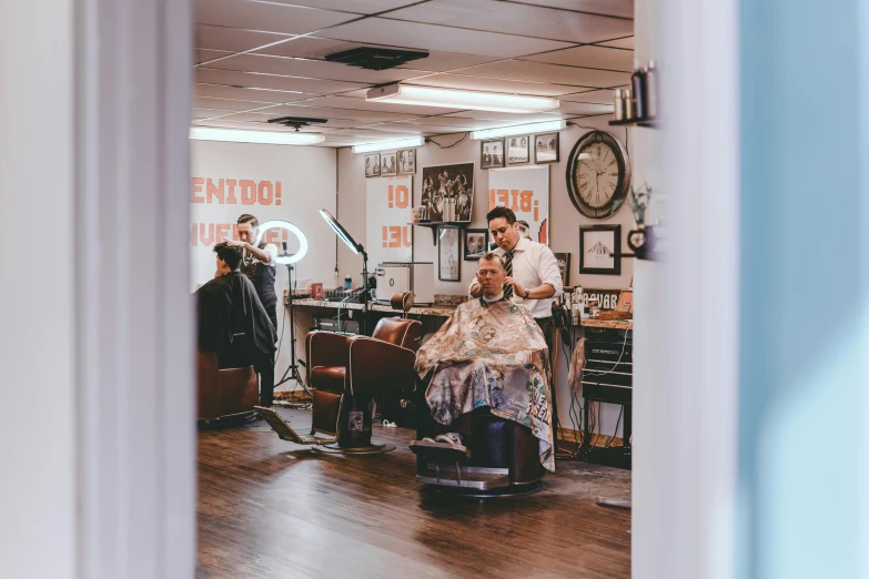 a man getting his hair cut in a barber shop, by Niko Henrichon, pexels contest winner, les nabis, traditional tattoo, overalls and a white beard, two buddies sitting in a room, thumbnail