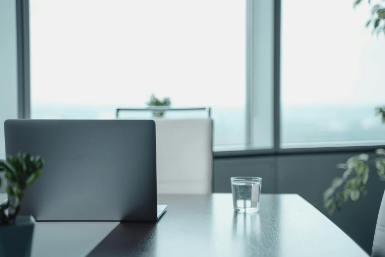 a laptop computer sitting on top of a wooden table, a computer rendering, unsplash, minimalism, clear glass wall, thirst, empty office, lachlan bailey