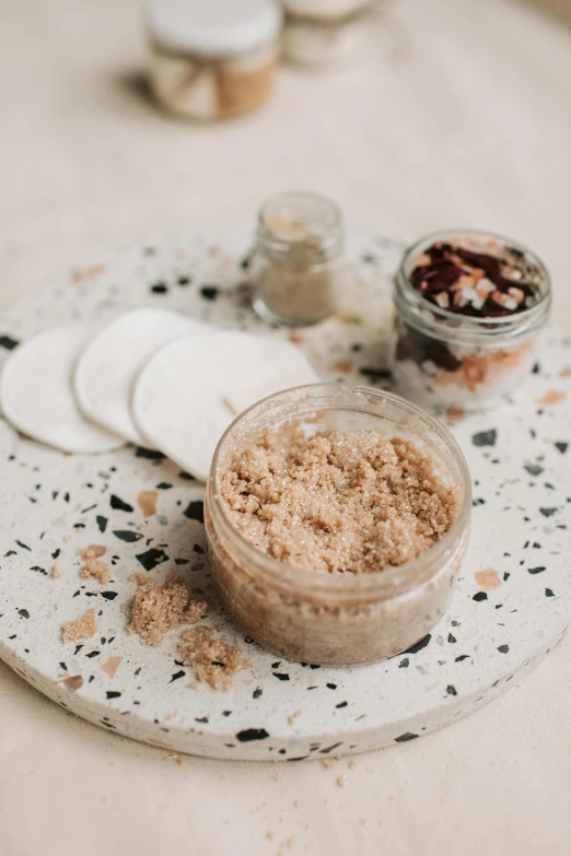 a close up of a plate of food on a table, jar on a shelf, sand particles, photoshoot for skincare brand, bath