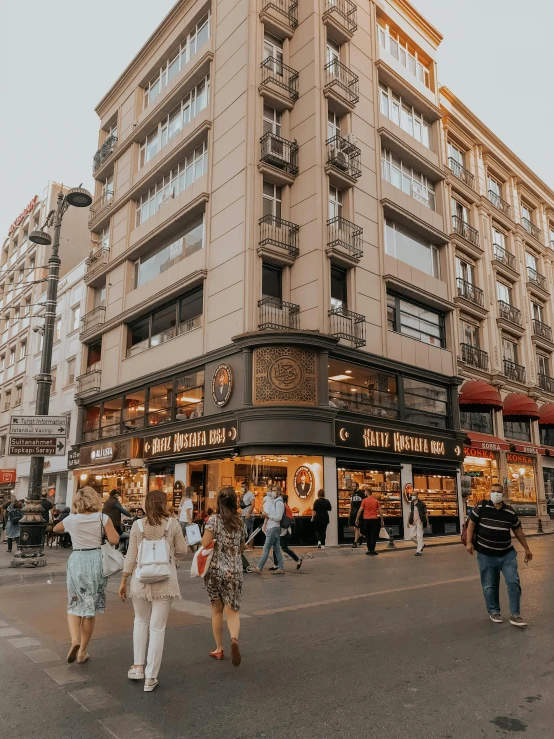 a group of people walking down a street next to tall buildings, bakery, madrid, background image, thumbnail