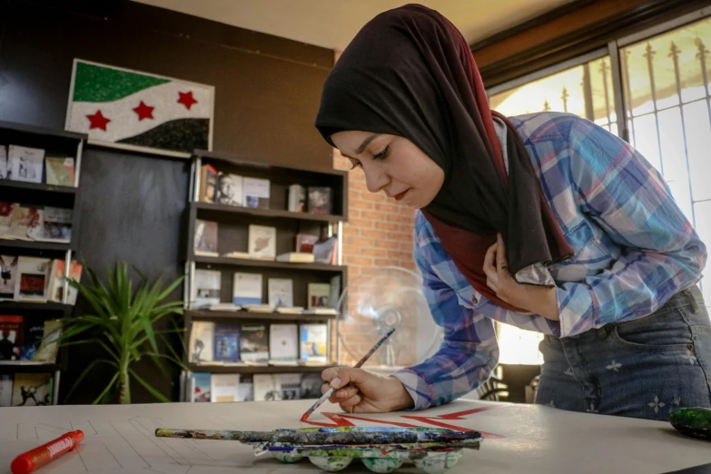 a woman in a hijab writing on a piece of paper, academic art, collaborative artwork, in a library, rojava, profile image