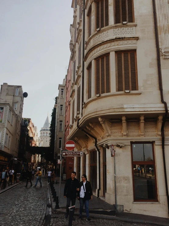 a group of people walking down a street next to tall buildings, a picture, renaissance, istanbul, background image, gothic quarter, low quality photo