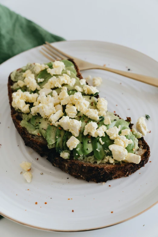 a white plate topped with a piece of bread covered in avocado, profile image, epicurious, thumbnail, daytime