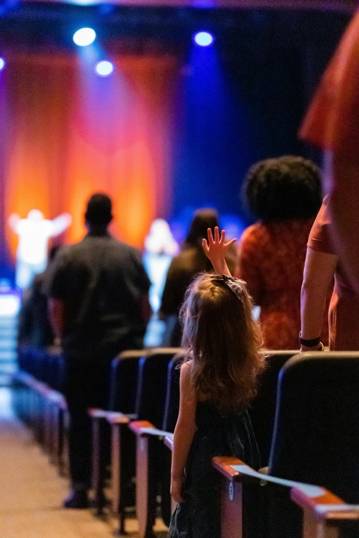 a group of people standing in front of a stage, worship, tiny girl looking on, in a sanctuary, stockphoto