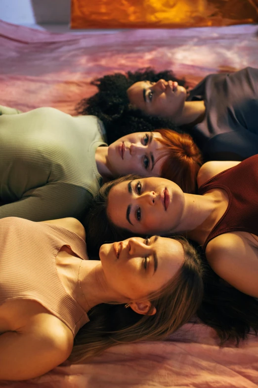 a group of women laying on top of a bed, inspired by Nan Goldin, trending on pexels, renaissance, ( redhead, multiple colors, looking sad, seen from below