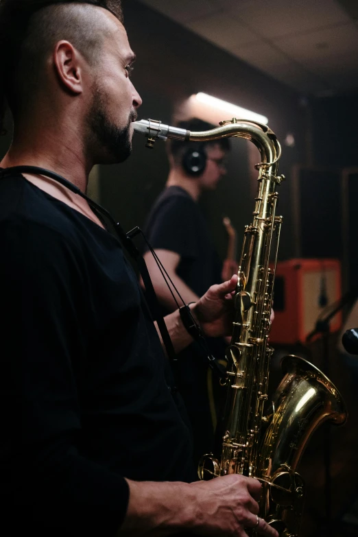 a man that is playing a saxophone in a room, an album cover, unsplash, in a studio, neck zoomed in, epk, cast