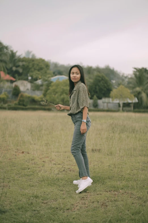a woman standing in a field flying a kite, by Basuki Abdullah, jeans and t shirt, 33mm photo, nostalgic 8k, small