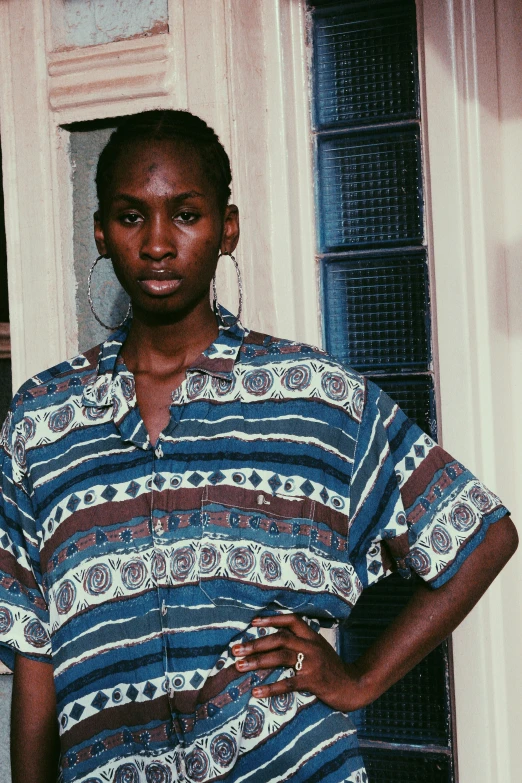 a man standing in front of a door with his hands on his hips, an album cover, inspired by Terrell James, trending on unsplash, renaissance, somali woman, wearing stripe shirt, 1990's sears portrait photo, paisley