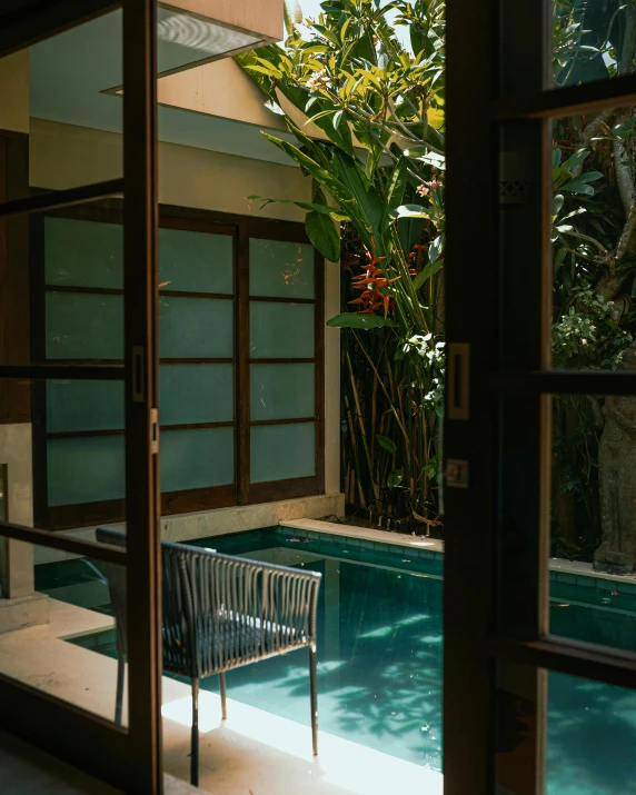 a chair that is sitting in front of a pool, inspired by Elsa Bleda, unsplash, light and space, indonesia, balcony door, with a fishpond and courtyard, hot tub