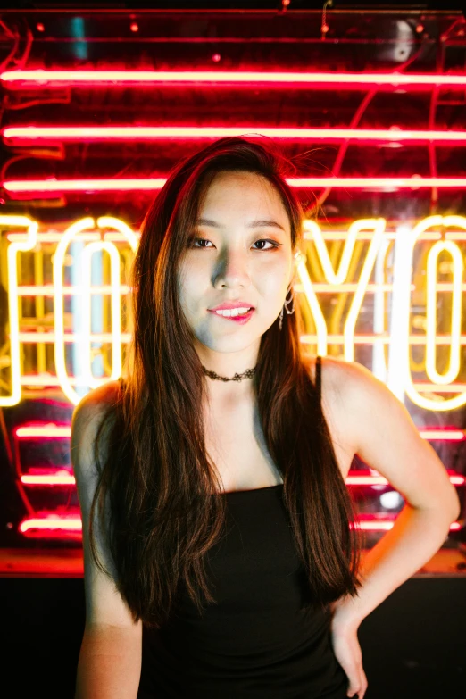 a woman standing in front of a neon sign, inspired by Yang J, pexels contest winner, young woman with long dark hair, looking up at camera, jen yoon, in a nightclub