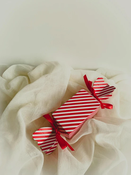 a candy bar wrapped in red and white striped paper, a picture, by Emma Andijewska, pexels contest winner, 🎀 🧟 🍓 🧚, white box, red fabric, full product shot